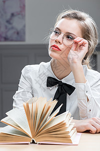 一个梦想中的年轻女人的肖像 戴着时装眼镜和书图片