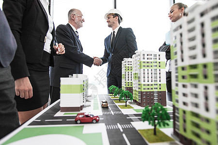 城市模型靠近房屋建模的商企人士建筑师蓝图不动产街道项目安全帽住房协议会议高楼背景