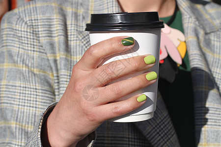 美丽的美甲女手握着纸板咖啡杯 黄色指甲油和绿猫眼设计图案程序咖啡绘画女孩美容师指甲手指治疗身体眼睛图片