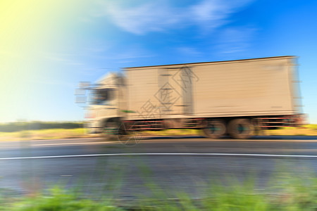 清晨光亮时公路上的卡车车轮模糊灯驾驶商业运输车后勤汽车运输货物沥青货运车辆图片