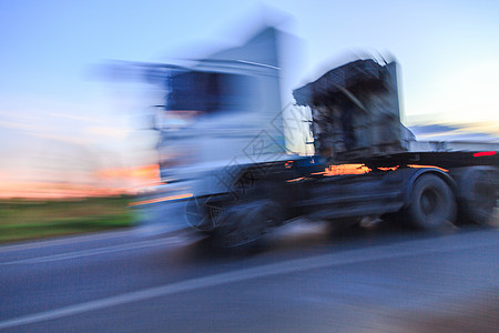 黄昏时公路上的卡车车轮闪光运输货运运动驾驶货物船运沥青天空商业车辆图片