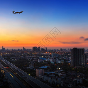 日出时在城市上空空中飞行的飞机休眠奢华速度假期商业航空航空公司建筑学翅膀客机空气图片