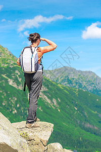 从山中背着背包的游客的背上石头女士远足运动闲暇活动天空岩石冒险高度图片