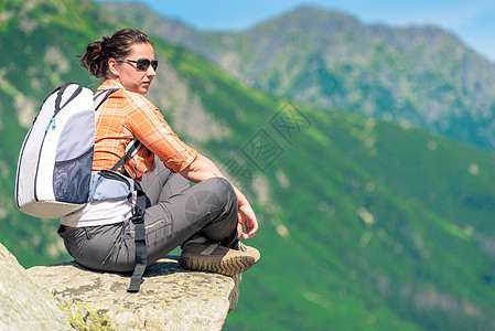女人坐在山上的石头上 背着背包 放松机智图片