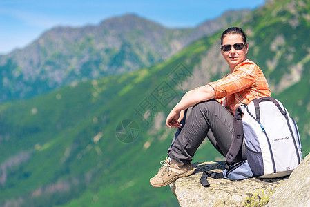 活跃的旅游者坐在山上的岩石上 背着一个背包图片