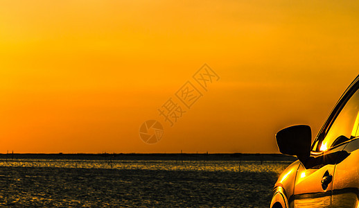 具有运动和现代设计的蓝色紧凑型 SUV 汽车停在海边的水泥路上 日落时分橙色的天空 环保技术 商业成功理念 混合动力汽车 汽车行背景图片