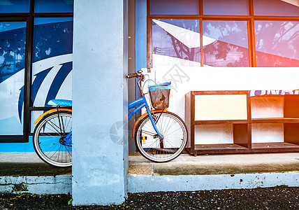 双轮车靠在木制鞋架旁的一根杆子上 放在一栋有照明灯的大楼水泥地板上街道倾斜运输车轮地面耀斑镜子自行车反射旅行图片