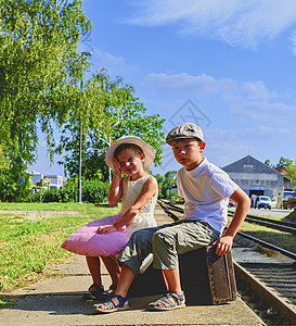可爱的小女孩和男孩在火车站 带着老式手提箱等火车 旅行 度假和童年的概念 旅游保险概念 假期旅行图片