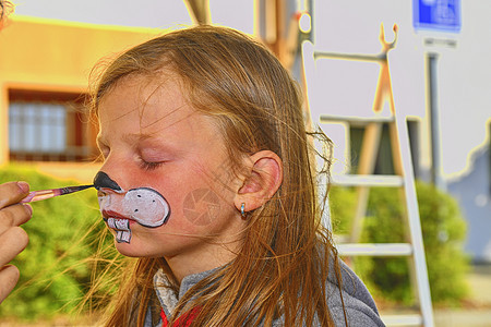 女人在户外画孩子的脸 娃娃脸彩绘 小女孩的脸被画脸师画成了兔子图片