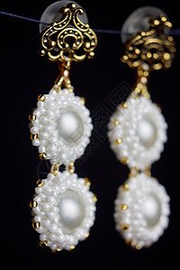手工制作的饰品由宏中的珠子制成 白色珠子的耳环 石头制成的耳环 漂亮的装饰品 白色珠子的耳环 黑色背景上的装饰品配件配饰商业风格图片