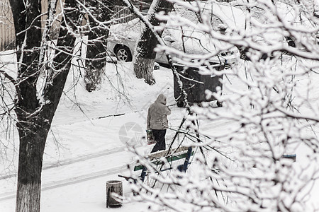 一个路过者在大雪中穿过寒雪的市区院子气候男人薄片降雪假期场景血统女孩男性风暴图片