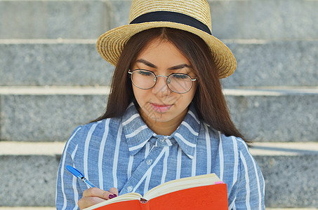 一名戴眼镜的亚洲青年学生身穿蓝条纹衬衫戴顶帽子的肖像城市眼镜互联网黑发快乐楼梯幸福学习女孩喜悦图片