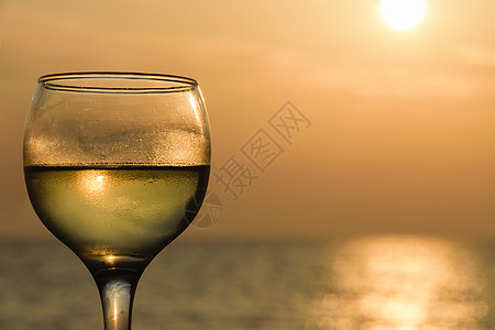 日落时装满白酒对抗海面玻璃的侧角角星形视图图片