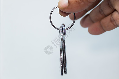 男性手拿着钥匙圈在白色背景下与复制空间区域隔离 车钥匙和块钥匙隔离在白色背景与钥匙圈图片