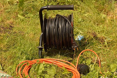 草地上带电电缆和延伸线的煤油 花园建筑工程用电工具 在果园中安装网络黑色力量工业技术通讯绳索工作水平橙子图片