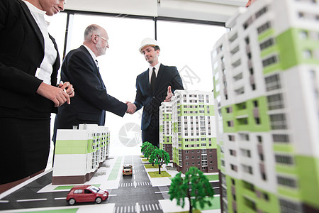城市模型建筑师和投资者的商务握手背景