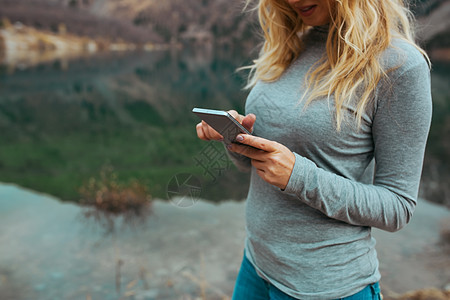 湖边使用智能手机的妇女短信闲暇自然娱乐工具女士人体反射媒体城市图片