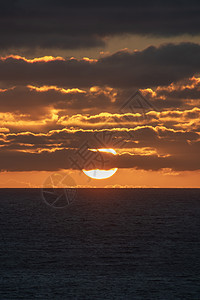 太阳几乎接近地平线 部分被红光云覆盖阳光蓝色日出海滩橙子海岸天空旅行海浪望远镜图片