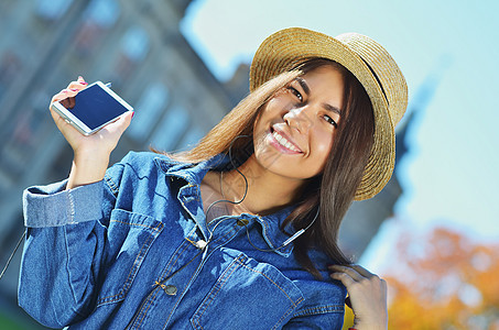 女学生在公园散步时手拿着电话 戴着稻草帽办公室邮件女孩青年活力手机衬衫商业街道太阳图片