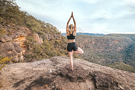 女性强度和瑜伽平衡的亚萨纳山悬崖壁图片