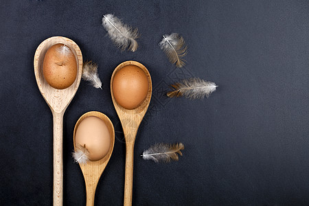 木勺和羽毛中的新鲜鸡蛋图片
