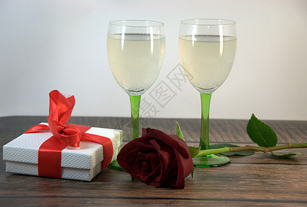 木桌上两杯香槟玫瑰和礼盒盒子假期夫妻生日桌子植物群风格酒杯装饰周年图片