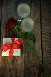 木桌上两杯香槟玫瑰和礼盒生日假期周年夫妻玻璃纪念日浪漫礼物盒子酒杯图片