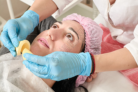 年轻女性在美容院做专业的面部按摩保健温泉福利压力身体皮肤科奶油按摩师保湿女士图片