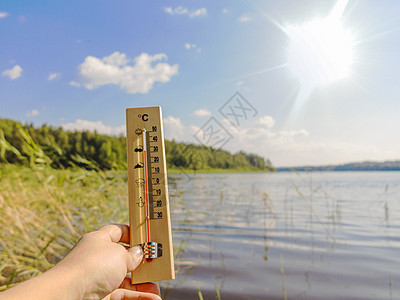 显示 30 摄氏度热量的温度计以湖水和蓝天为背景在阳光下海浪海滩旅行假期天气高温地平线蓝色季节太阳图片