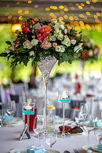 装上鲜花和餐盘的婚桌桌子玻璃餐巾派对椅子蜡烛盘子桌布玫瑰花束图片