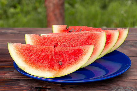 在木制桌子上的蓝色板块上 切成熟熟熟的红西瓜食物盘子饮食热带水果浆果花园甜点营养图片