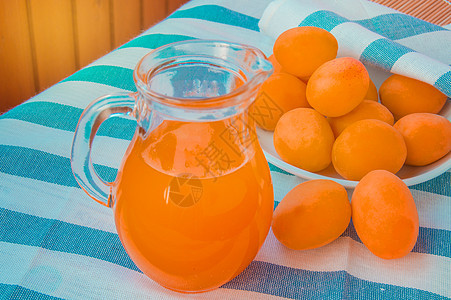 夏季饮料 - 在玻璃壶里喝新鲜的杏子汁 紧挨着葡萄酒旁边的是条纹餐巾纸图片