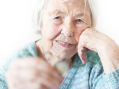 96岁坐在家里桌桌上的有96岁幸福的年长老人 对手里拿着一枚硬币感到快乐 为退休和规划财务而储蓄保险养老金情感现金兴趣钱包女性报图片