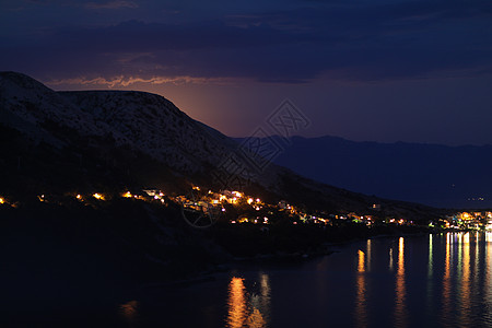 月光下的夜景从克罗地亚的岩石山到亚得里亚海沿岸的城市 不同的色调鸟瞰图社区海岸线海景蓝色地标天线别墅风景大地图片