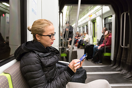 年轻女孩在地铁的手机屏幕上阅读商业过境管子航程女性通勤者运输游客电话日程图片