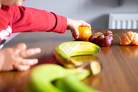 夜空月婴儿手操纵木制桌上不同水果的婴儿手厨房用途知识孩子们手指橙子指甲紫色童年线条背景
