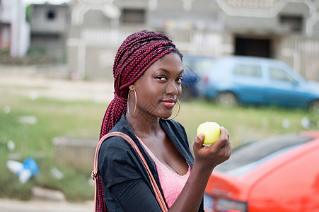 年轻女人拿着苹果看着摄像机 (笑声)图片