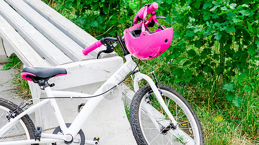 为公园内戴粉红色保护头盔的少女提供自行车青少年齿轮车辆女孩闲暇运输绿色运动车轮旅行图片