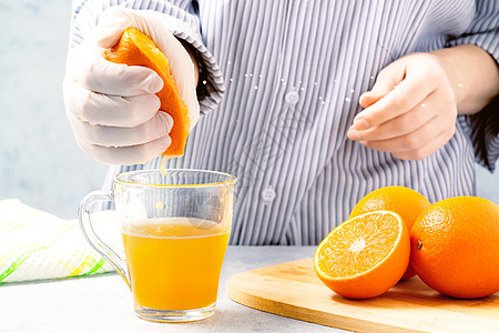 女人把橙汁挤在玻璃杯里细流玻璃水果女士饮料挤压器橙子营养烹饪早餐图片