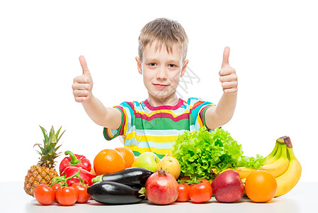 开心的男孩在桌子上 与一堆新鲜蔬菜和水果图片