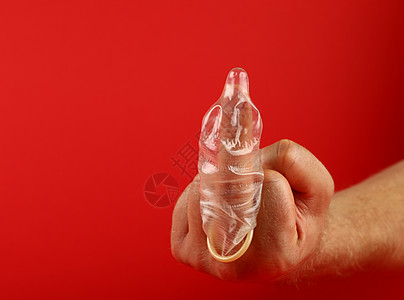 近身的男子手与保险套 在手指上用安全套男人卫生手势红色风险侮辱避孕用法预防控制图片