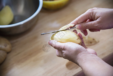 烹饪新鲜马铃薯的人在厨房准备食物     土豆烹饪概念营养木头淀粉女士蔬菜美食皮肤工作桌子厨师图片
