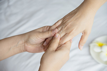 在干净的白色床背景上进行手部水疗按摩  人们可以通过手部按摩服务放松身心身体沙龙指甲治疗拇指护理顾客女士皮肤治疗师图片