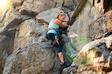 美丽的女人爬上山中的岩石 冒险和极限运动概念女孩肾上腺素爱好太阳石头挑战勇气悬崖日落风险图片