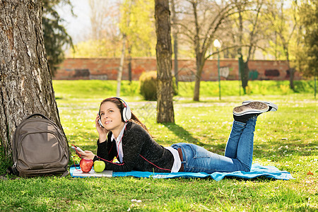 年轻女孩在公园里听音乐图片