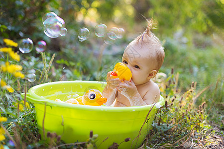 盆子里的托德勒男孩 用泡泡和鸭玩具洗澡气泡婴儿身体喜悦儿童浴室浴缸生态小鸭子太阳图片