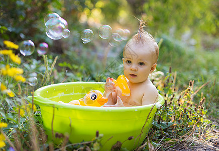 盆子里的托德勒男孩 用泡泡和鸭玩具洗澡浴室儿童盆地黄色享受太阳浴缸身体孩子生态图片