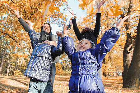 家庭在秋季公园玩耍女士孩子父母树叶妈妈快乐孩子们男人女性叶子图片