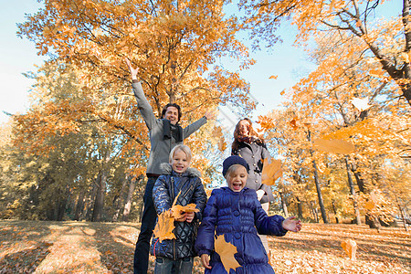 家庭在秋季公园玩耍叶子孩子树叶童年男人幸福季节微笑女士喜悦背景图片