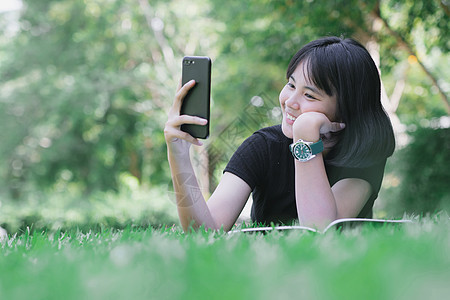 女孩坐在花园的草坪上学生草地笔记本女士假期学习阳光工作童年技术图片